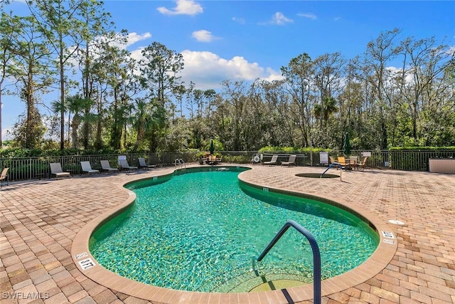 community pool with a patio and fence