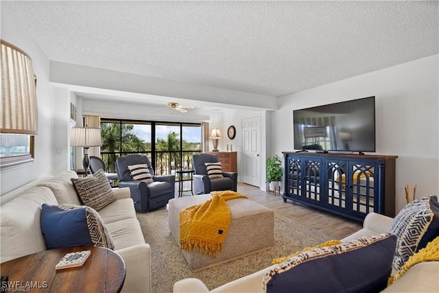 living room featuring a textured ceiling, light hardwood / wood-style floors, and ceiling fan