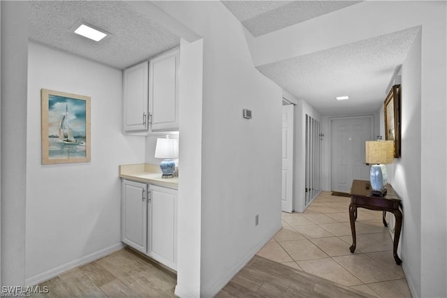 hallway with light hardwood / wood-style floors and a textured ceiling