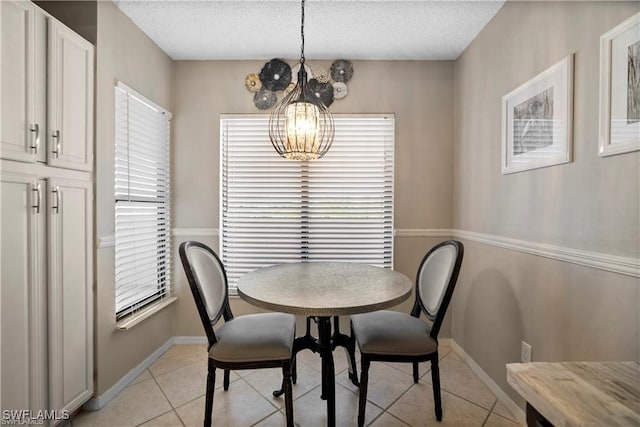 7430 Lake Breeze Dr Unit 402, Fort Myers, FL 33907 - dining room with light tile patterned floors, a chandelier, a textured ceiling, and baseboards