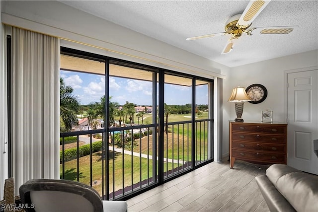 bedroom with multiple windows, a textured ceiling, light hardwood / wood-style floors, and ceiling fan