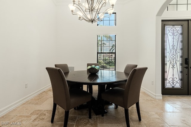 dining space featuring ornamental molding, a towering ceiling, and a chandelier