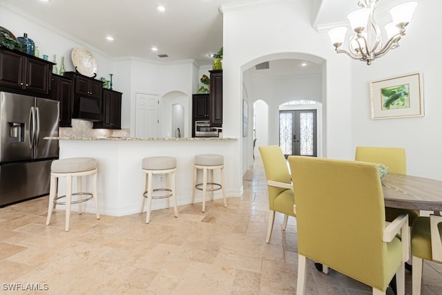 kitchen featuring kitchen peninsula, appliances with stainless steel finishes, light stone countertops, french doors, and ornamental molding