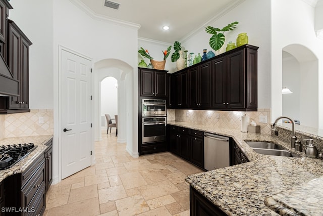 kitchen featuring backsplash, crown molding, sink, appliances with stainless steel finishes, and light stone counters