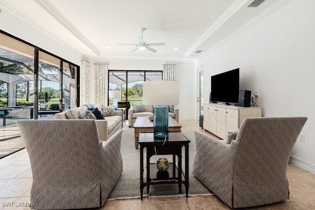 living room featuring a raised ceiling, a wealth of natural light, ornamental molding, and ceiling fan