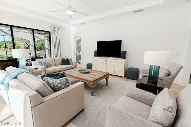 living room featuring ceiling fan, a raised ceiling, and crown molding