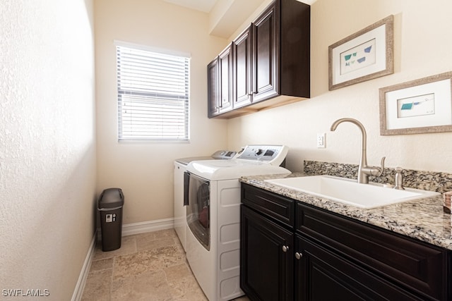 clothes washing area with cabinets, washer and dryer, and sink