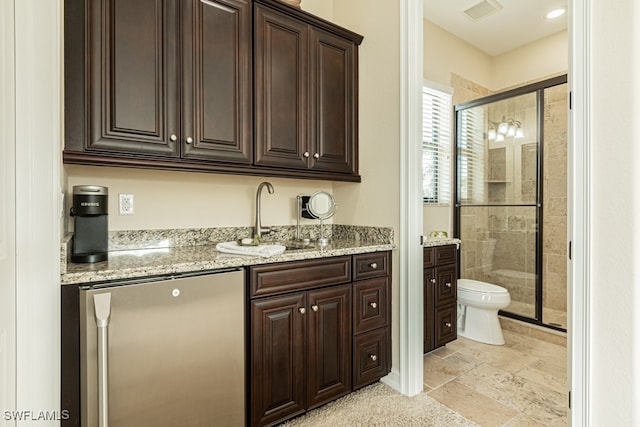 interior space with light stone countertops, stainless steel fridge, dark brown cabinetry, and sink