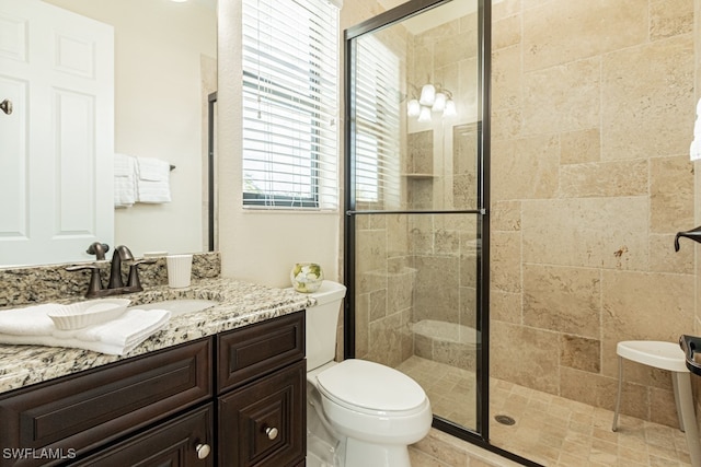 bathroom with vanity, toilet, and a shower with door