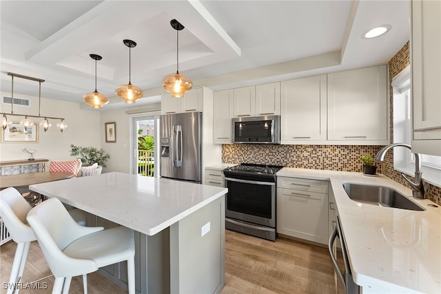 kitchen with a tray ceiling, sink, white cabinets, and appliances with stainless steel finishes