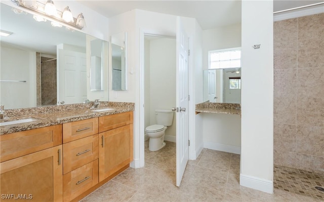 bathroom featuring a tile shower, tile patterned flooring, vanity, and toilet