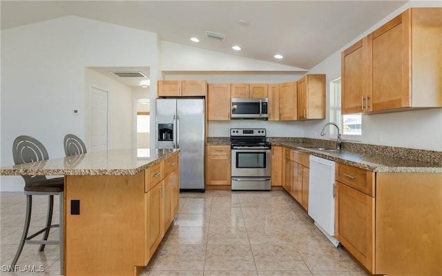 kitchen featuring a breakfast bar, a center island, sink, vaulted ceiling, and stainless steel appliances