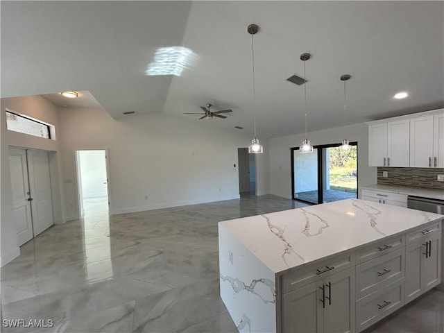 kitchen with ceiling fan, lofted ceiling, a kitchen island, white cabinets, and backsplash