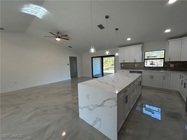 kitchen with vaulted ceiling, a center island, pendant lighting, decorative backsplash, and white cabinets