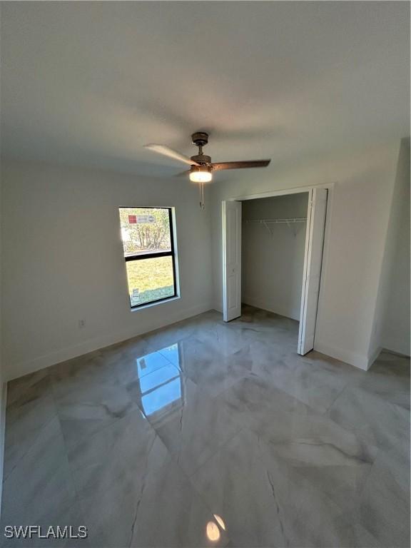 unfurnished bedroom with ceiling fan and a closet