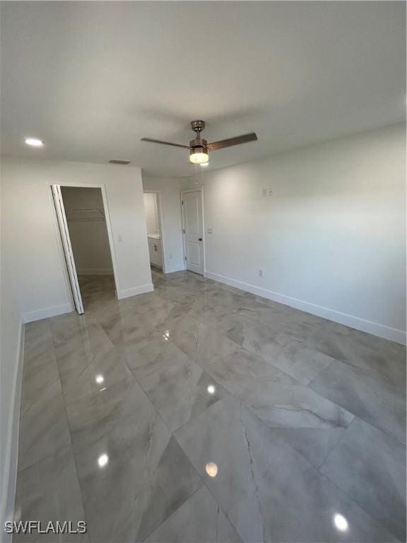 unfurnished bedroom with ceiling fan, a spacious closet, and a closet