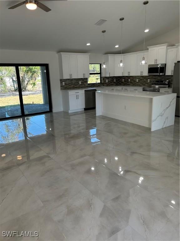 kitchen with white cabinets, stainless steel appliances, vaulted ceiling, and pendant lighting