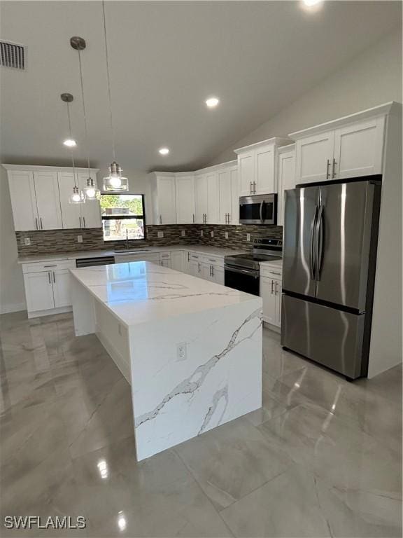 kitchen featuring vaulted ceiling, hanging light fixtures, stainless steel appliances, a kitchen island, and white cabinets