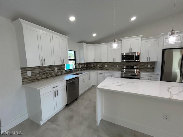 kitchen featuring vaulted ceiling, stainless steel appliances, white cabinetry, and hanging light fixtures