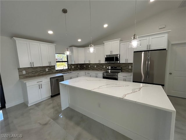 kitchen featuring stainless steel appliances, a kitchen island, white cabinetry, decorative light fixtures, and lofted ceiling