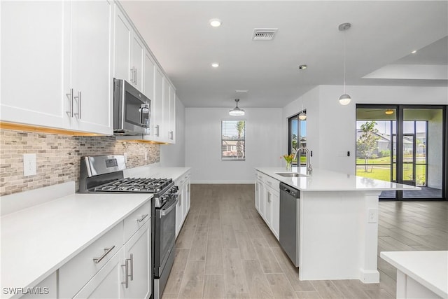 kitchen featuring decorative backsplash, appliances with stainless steel finishes, sink, decorative light fixtures, and white cabinets