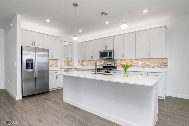 kitchen featuring backsplash, an island with sink, pendant lighting, white cabinets, and appliances with stainless steel finishes