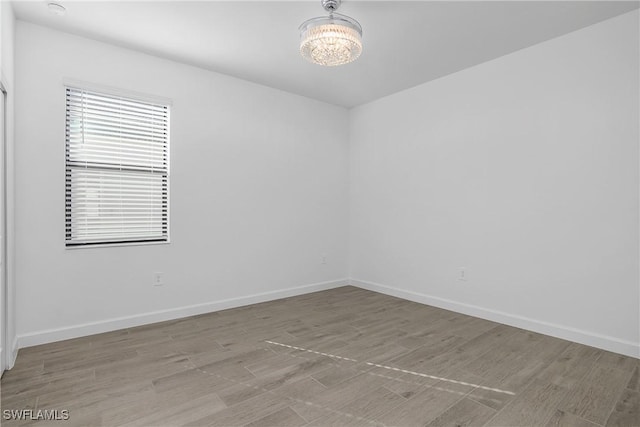 spare room featuring light hardwood / wood-style floors and a notable chandelier