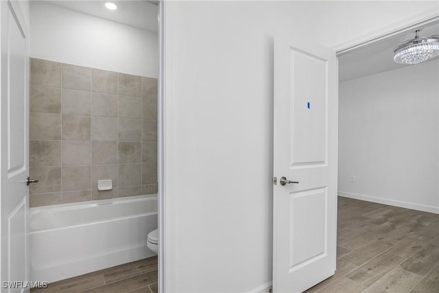 bathroom with toilet and tiled shower / bath