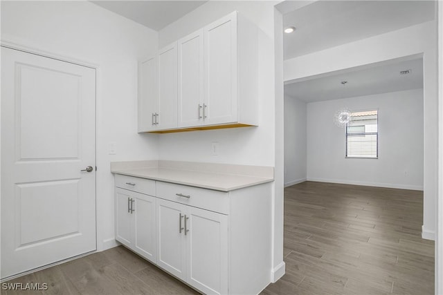 21079 Hallandale Dr, Estero, FL 33928 - kitchen with white cabinetry, wood finished floors, and light countertops