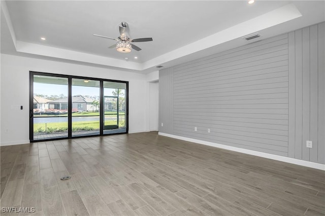 spare room featuring ceiling fan, wood walls, and a tray ceiling