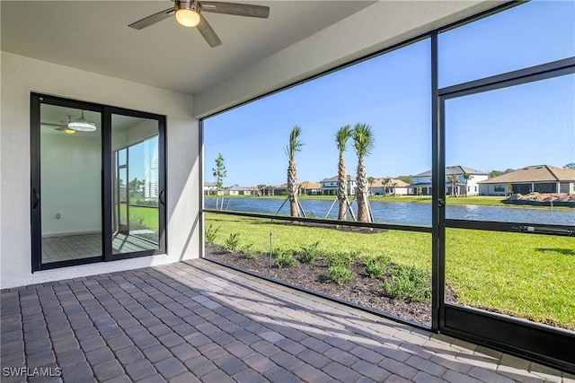 unfurnished sunroom featuring ceiling fan and a water view