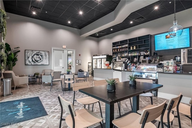 dining area with indoor bar, a towering ceiling, and light parquet flooring