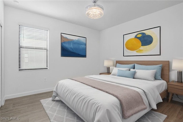 bedroom with an inviting chandelier and hardwood / wood-style flooring