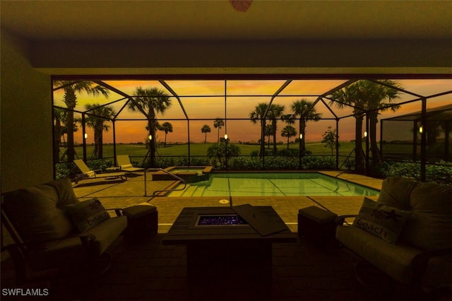 patio terrace at dusk featuring a lanai and an outdoor living space with a fire pit