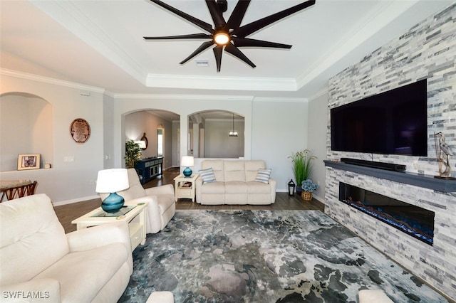 living room featuring crown molding, ceiling fan, a tray ceiling, and a fireplace