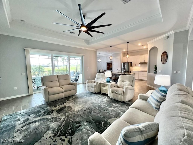 living room featuring sink, ornamental molding, a raised ceiling, and ceiling fan