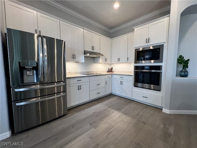 kitchen with appliances with stainless steel finishes, white cabinets, hardwood / wood-style flooring, ornamental molding, and light stone counters