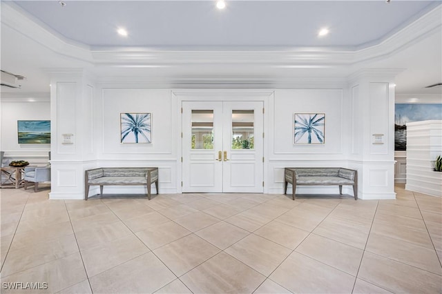 tiled entrance foyer with french doors, ornamental molding, and a raised ceiling