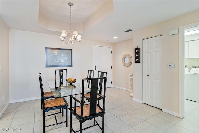 dining space with a chandelier, separate washer and dryer, a raised ceiling, and light tile patterned floors