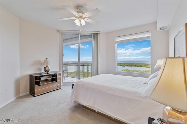 carpeted bedroom featuring a water view, ceiling fan, multiple windows, and access to outside