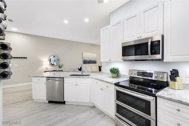 kitchen featuring kitchen peninsula, stainless steel appliances, white cabinets, and sink