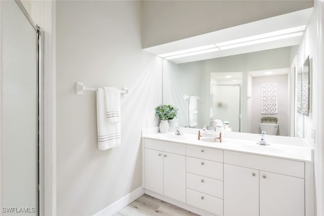 bathroom featuring hardwood / wood-style floors, vanity, toilet, and a shower with shower door