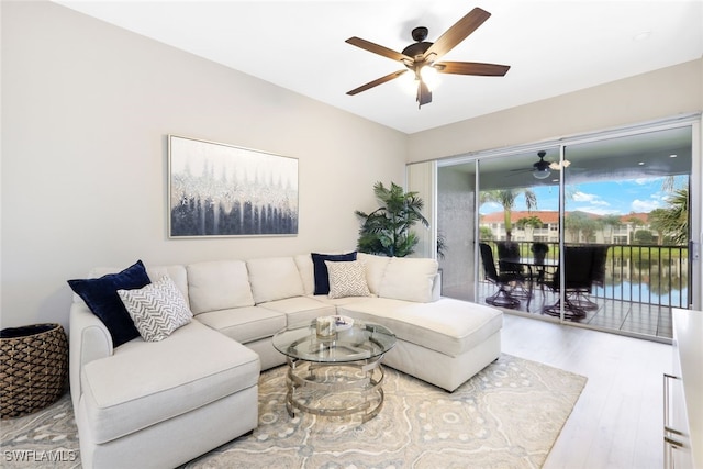 living room with hardwood / wood-style floors, ceiling fan, and a water view