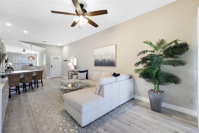 living room with ceiling fan, light wood-type flooring, and sink