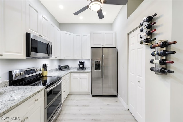 kitchen with light hardwood / wood-style flooring, ceiling fan, light stone countertops, appliances with stainless steel finishes, and white cabinetry