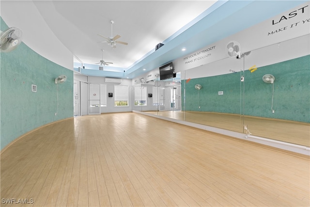 exercise area with an AC wall unit, ceiling fan, and wood-type flooring