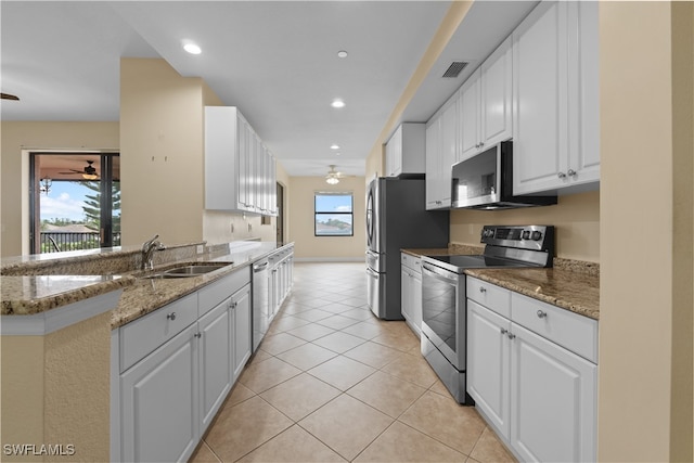 kitchen with white cabinets, appliances with stainless steel finishes, and a wealth of natural light