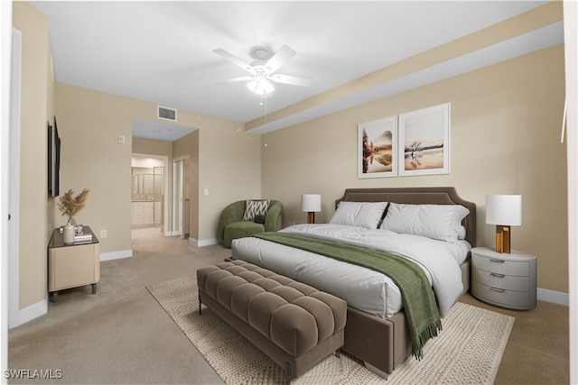 carpeted bedroom with ensuite bath and ceiling fan