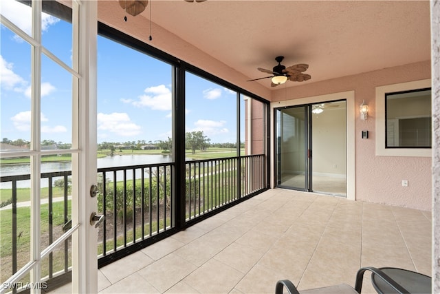 unfurnished sunroom featuring a water view and ceiling fan