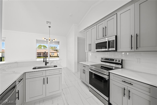 kitchen featuring gray cabinetry, sink, vaulted ceiling, decorative light fixtures, and stainless steel appliances